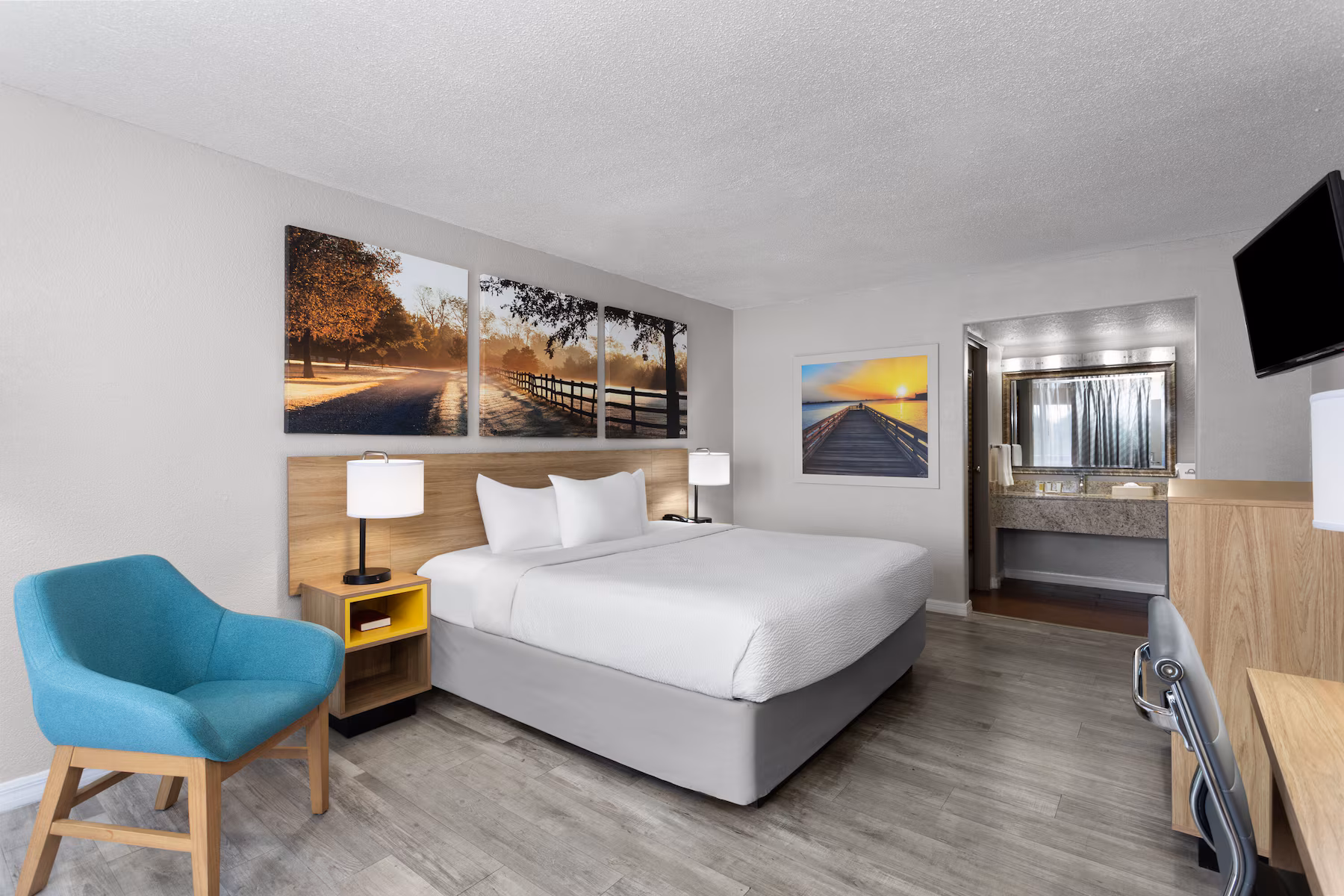 King room with lounge chair, artwork and vanity beyond