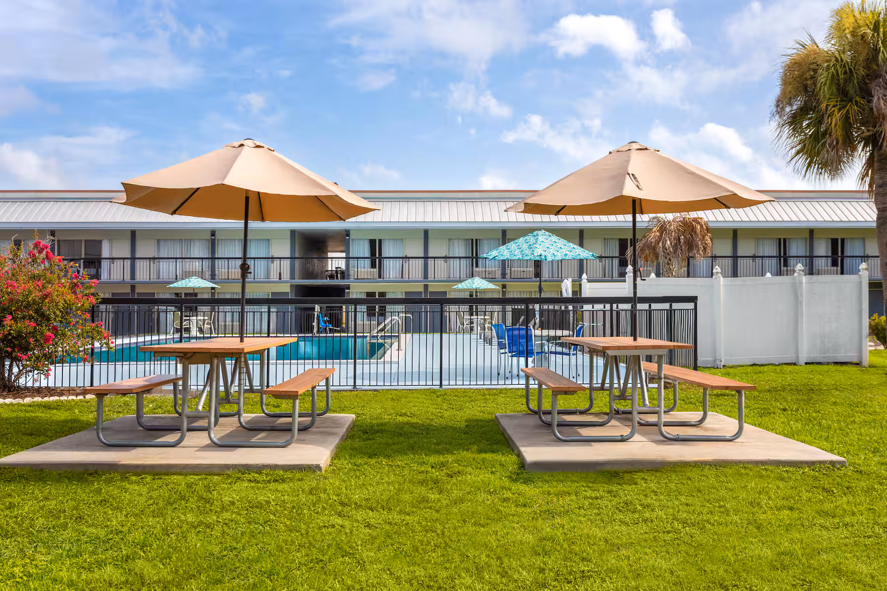 Shaded picnic tables on the lawn beside the pool